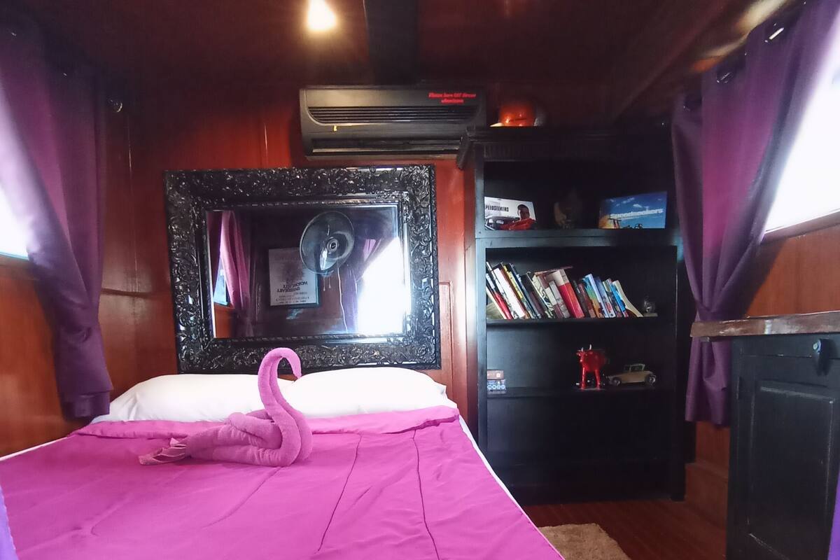 Quarto com uma cama, espelho, estante de livros e lareira.