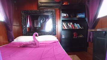 Una habitación con cama, espejo, estantería y chimenea.