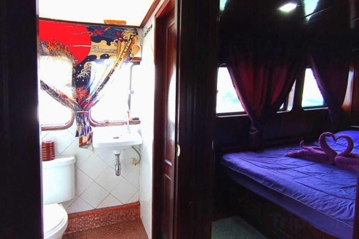 Una habitación pequeña y funcional con cama, ventana y lavamanos.