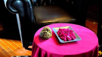A black leather sofa with a cushioned seat and backrest, a small round table with a pink tablecloth, and a framed picture on the wall.