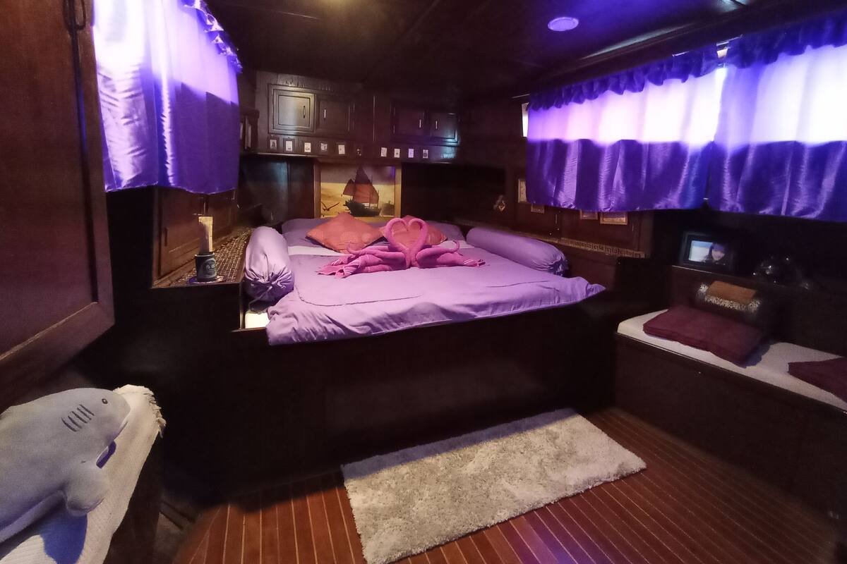 Um quarto aconchegante com uma cama, uma mesa pequena e uma janela com cortinas.