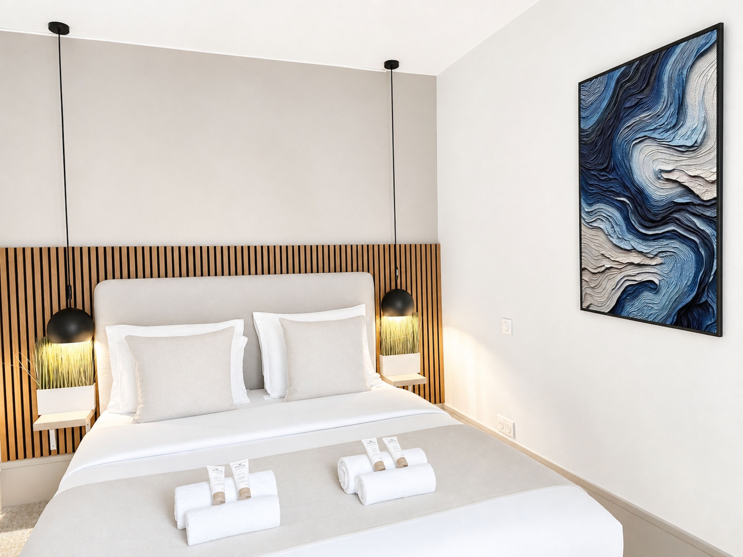 Una habitación de hotel moderna con una cama grande, dos lámparas de noche y una obra de arte colgada en la pared.