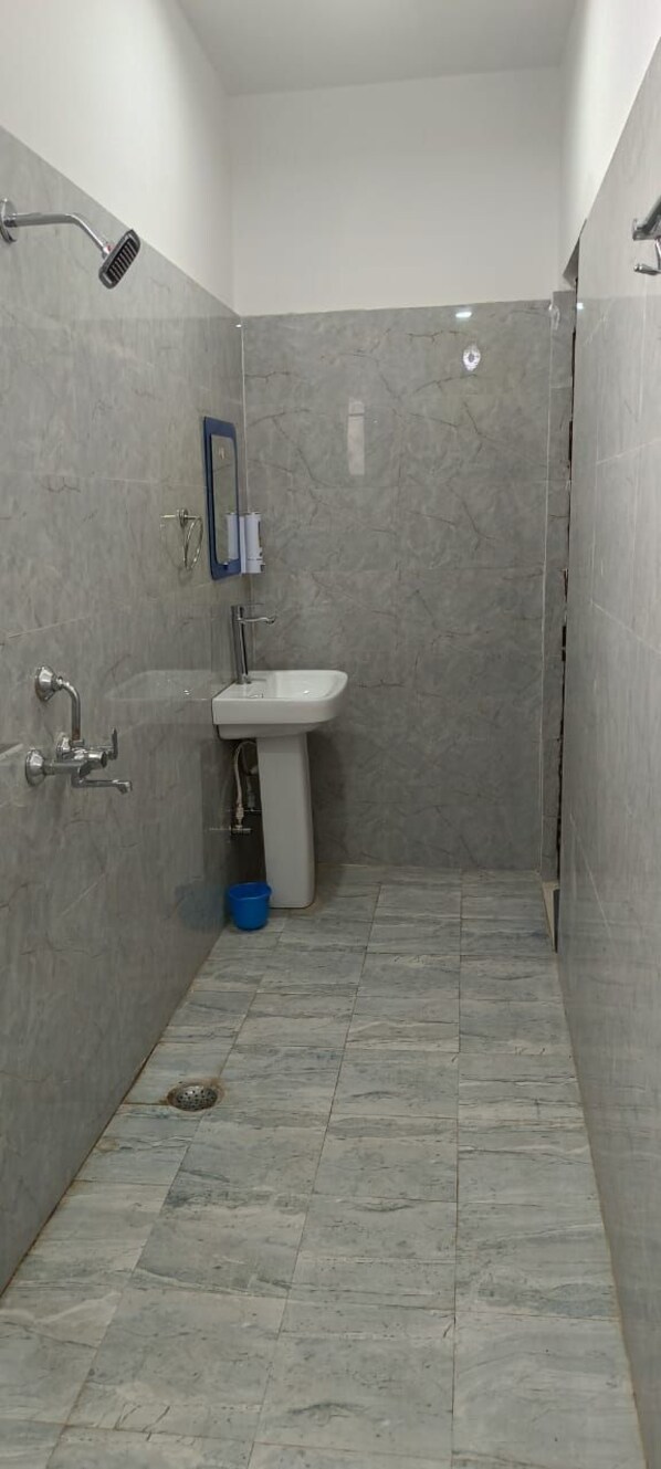 Un baño pequeño y cerrado con lavamanos, espejo y ducha.