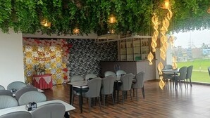 Ravintola, jonka teemana on syntymäpäivä, ja jossa on koristeellinen seinä, roikkuvia kasveja ja näkymä kaupungin ylle.