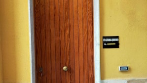 A wooden door with a brass handle, a stone base, and a yellow wall with a sign reading "CTA Catania Aeroporto". - CTA Catania Aeroporto Fontanarossa (Catania)