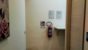 A hallway with a fire extinguisher, a sign indicating a no-smoking area, and a door at the end. - CTA Catania Aeroporto Fontanarossa (Catania)
