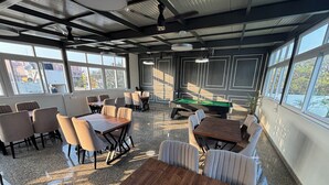 Un ambiente interno moderno con tavolo da biliardo, zone relax e ampie finestre.