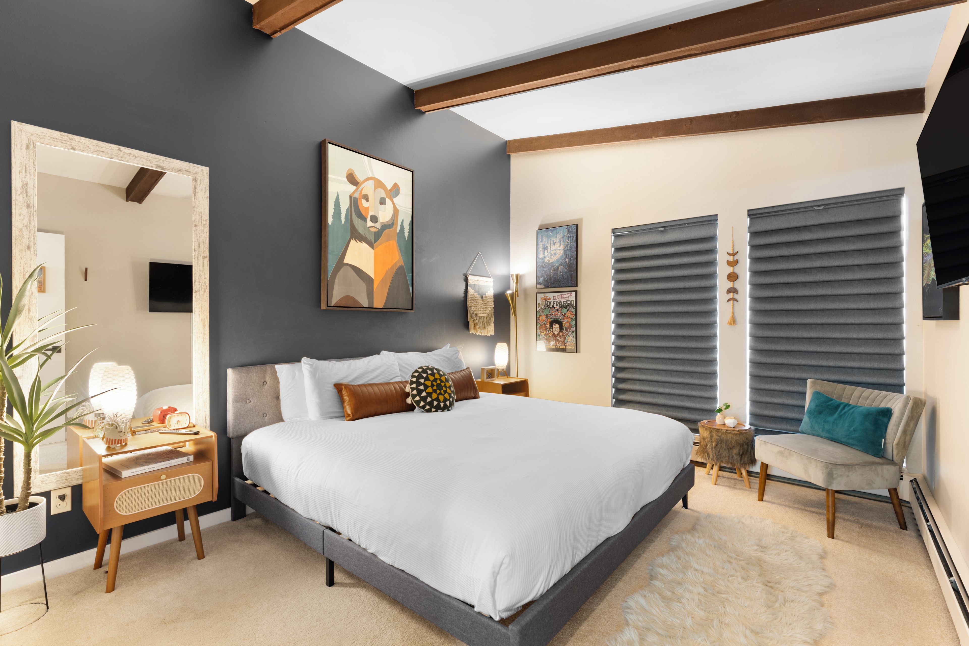 Unwind in your stylish retreat with vaulted ceilings, warm wood beams, and a plush king bed. The cozy seating nook and modern artwork create the perfect space to recharge.
