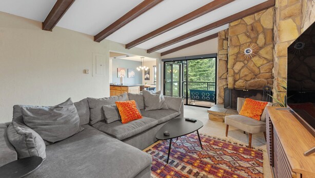 A modern living room with a stone fireplace, a sectional sofa, and a television.