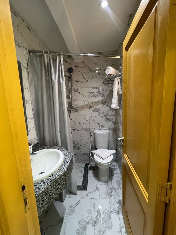 Ein Badezimmer mit Marmorboden, einer Badewanne, einer Toilette und einem Waschbecken.