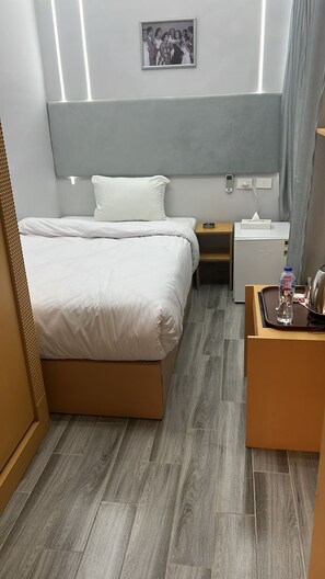 Ein Hotelzimmer mit Bett, Nachttischen, einem kleinen Kühlschrank und einem Spiegel.