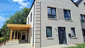 A modern two-story building with a brick facade, large windows, and a covered entrance area. - Vacation home Wolke7, with garden, 250 meters to the lake (Lembruch)