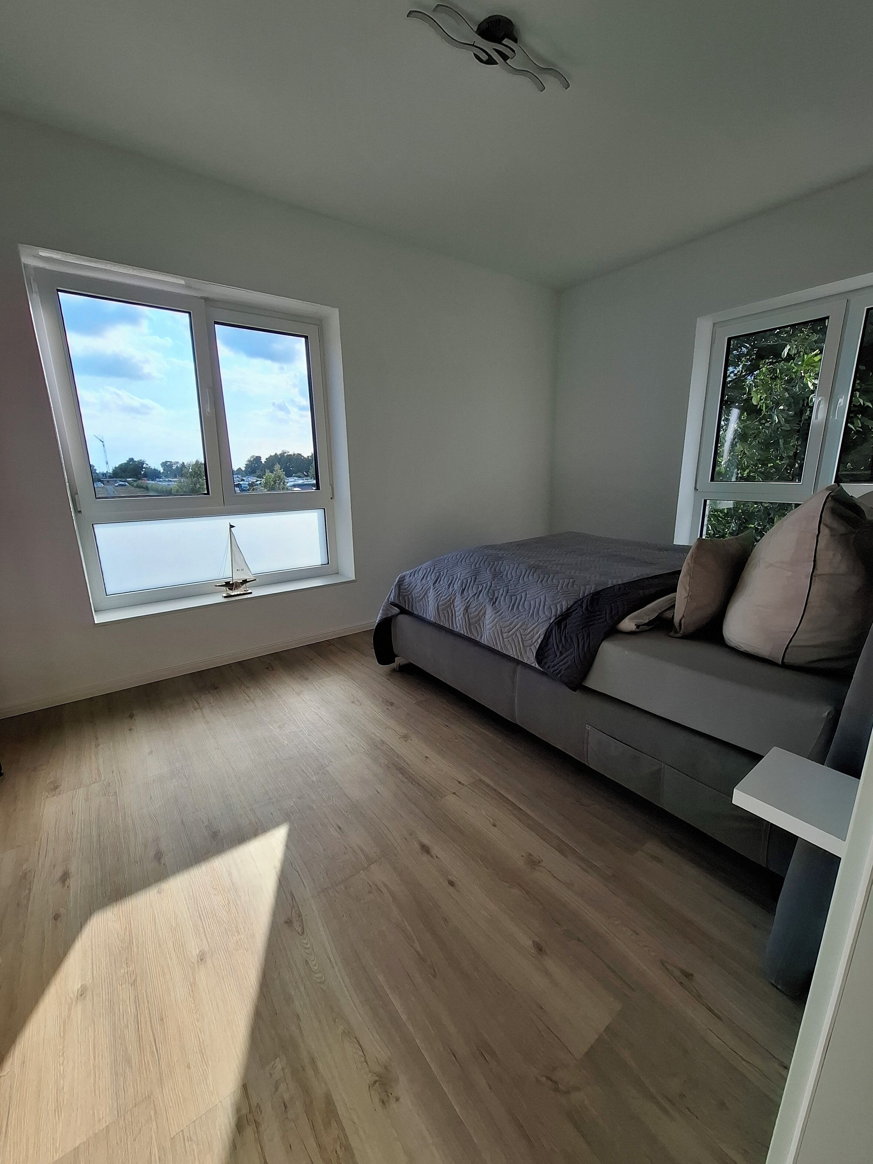 A bedroom with a bed, two windows, and a ceiling fan.
