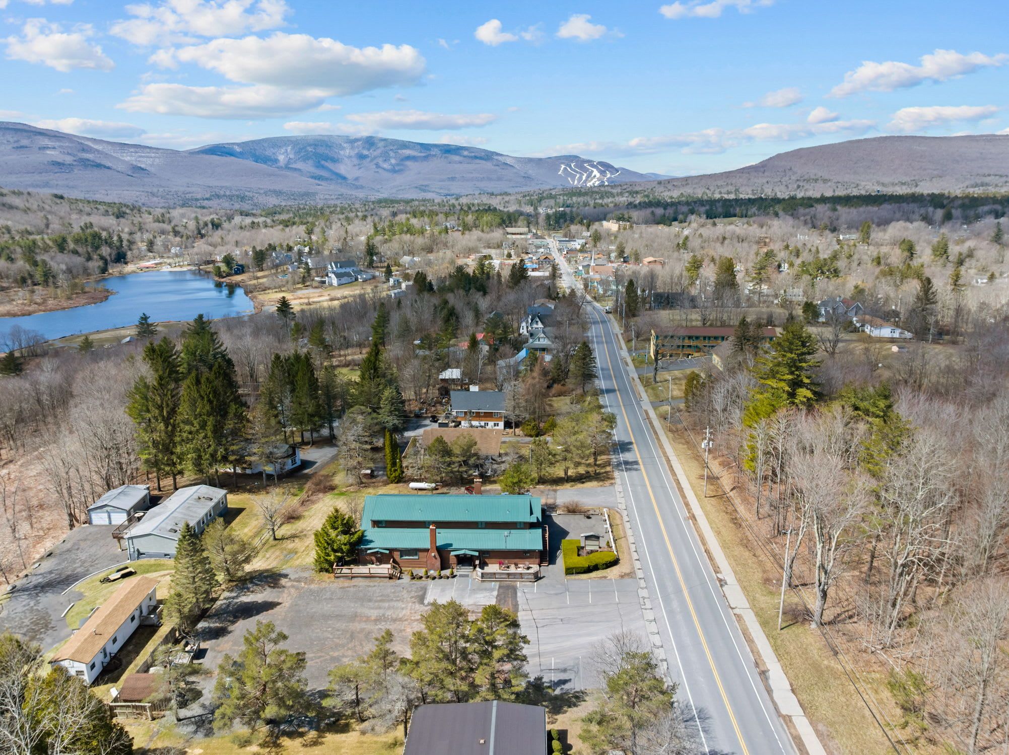 A residential area with a main road, houses, and a lake.