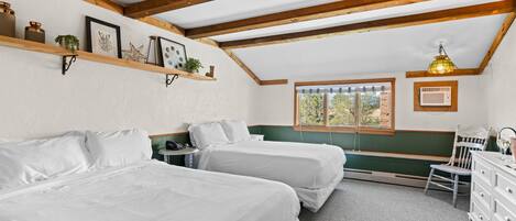 Un dormitorio con dos camas, vigas de madera, un ventanal y un escritorio con una silla.