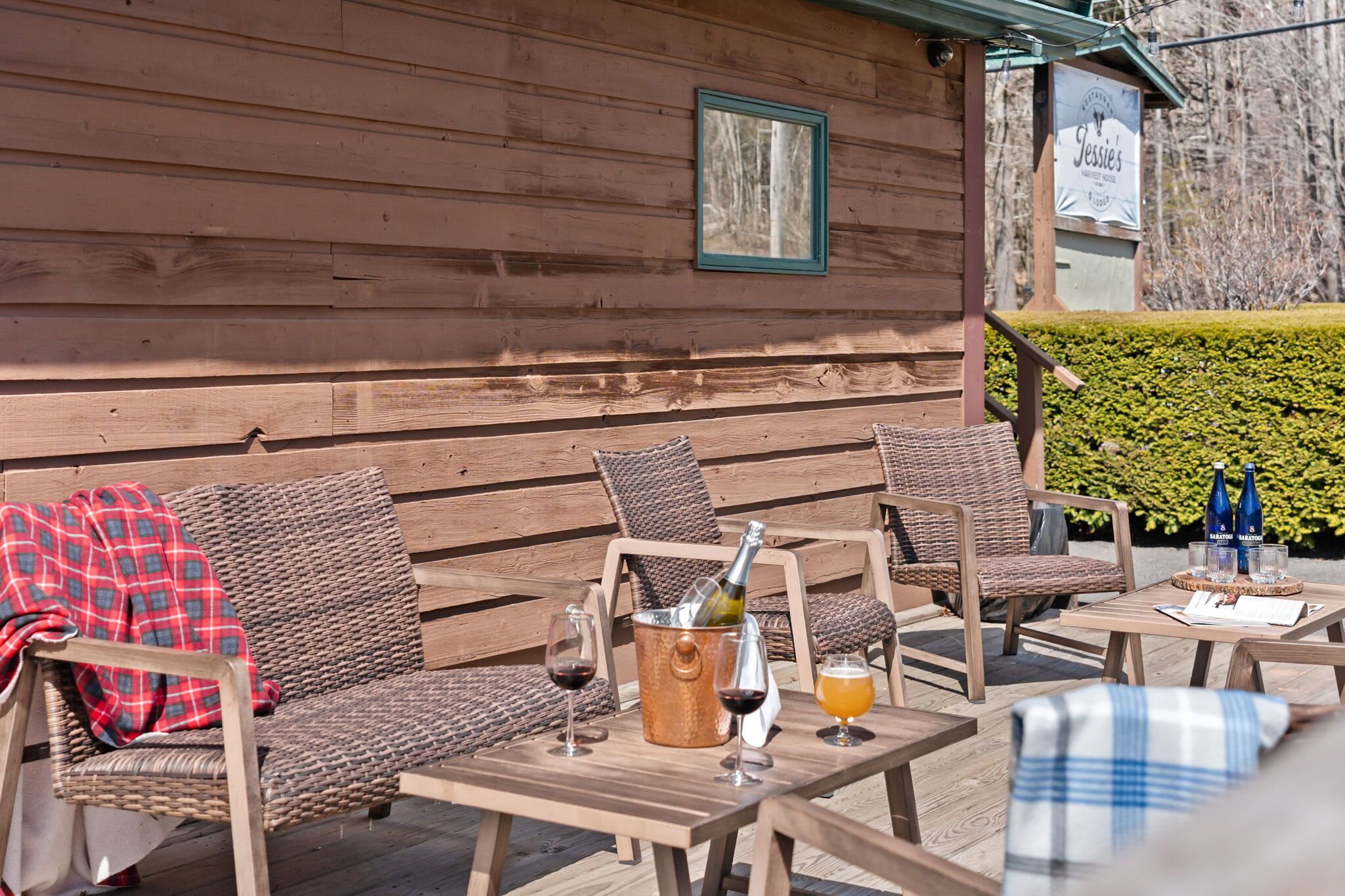 A wooden cabin with wicker furniture, a table with a bottle of wine, and a menu.