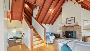 Un amplio salón con una escalera de madera, una chimenea y una zona de estar acogedora.