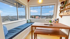 Una habitación acogedora con un banco y una mesa de madera, y ventanas amplias que dan a la campiña.