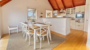 Una cocina amplia con vigas de madera, armarios blancos y una isla central.