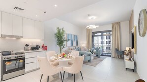 Een modern appartement met keuken, eethoek en woonkamer. Het heeft een groot raam, een balkon en uitzicht op de stad.