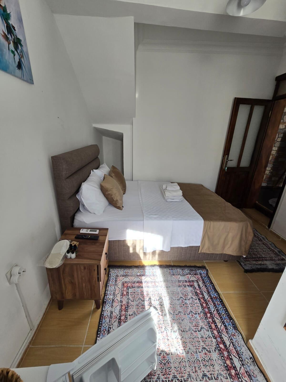 Un dormitorio pequeño y bien iluminado con cama, mesita de noche y alfombra.
