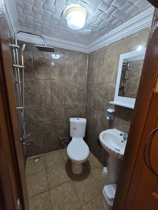 A bathroom with a shower, toilet, sink, and a mirror. - QMEYDANN (Ayvalik)