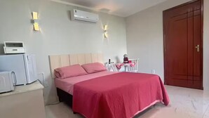 A bedroom with a bed, a desk, and a wardrobe. - Suite with air conditioning in Praia Seca - Araruama. (Araruama)