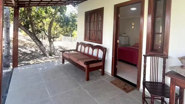 A covered patio area with a wooden bench, a table, and chairs. - Suite with air conditioning in Praia Seca - Araruama. (Araruama)