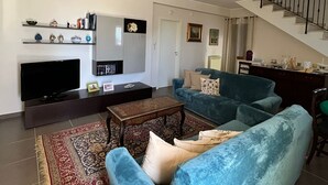 A living room with a TV, sofa, coffee table, and a staircase.