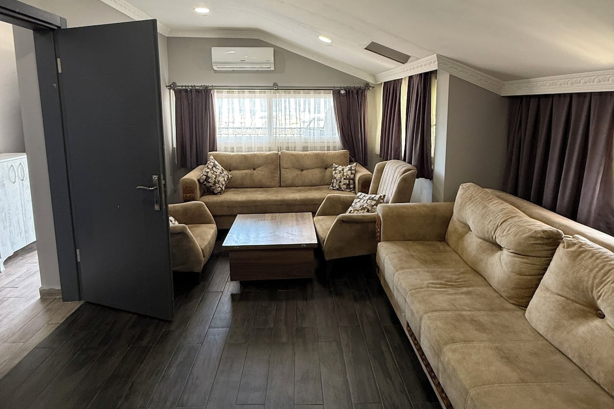 A spacious living room with a large sectional sofa, a coffee table, and dark wooden flooring.