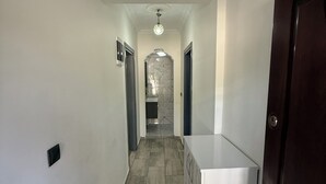 En gang med en marmorvæg, en loftlampe og en dør til højre.