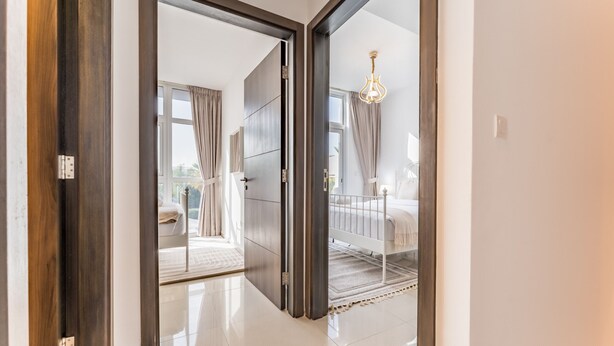 A modern hotel room with a large sliding door leading to a balcony. - Community and Pool View 3BR Townhouse, Minutes from Desert Camp,DAMAC Hills 2 (Dubai)