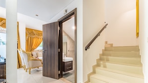 A modern interior with a staircase, a dining area with golden curtains, and a visible bathroom. - Community and Pool View 3BR Townhouse, Minutes from Desert Camp,DAMAC Hills 2 (Dubai)