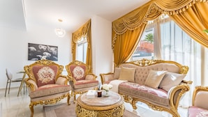 A luxurious living room with ornate furniture, a round coffee table, and a large window with curtains. - Community and Pool View 3BR Townhouse, Minutes from Desert Camp,DAMAC Hills 2 (Dubai)