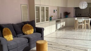 A modern living room with a grey sofa, a round ottoman, and a striped rug.