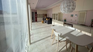A modern kitchen with white cabinets, a dining table with chairs, and a large decorative light fixture.