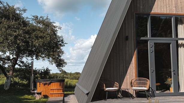 Ein modernes Haus mit geneigtem Dach, einer Holzdiele und einer großen Glasdoor.
