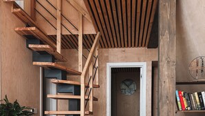 Ein modernes Interieur mit einer Holztreppe, einem grauen Sofa und einem Couchtisch aus Holz.