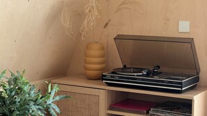 Ein Holzkabinett mit Plattenspieler und einer hohen Vase.