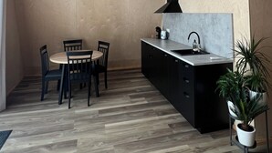 Eine moderne Küche mit Essbereich, mit Holzboden, einer zentralen Kochinsel mit Spüle und einer schwarzen Ablage über der Arbeitsplatte.