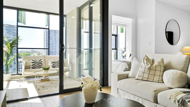 A modern living room with a sofa, a coffee table, and a vase of flowers. - Waterloo Serenity Suite (Waterloo)