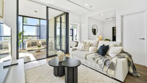A modern living room with a sofa, coffee table, and a view of the city through large windows. - Waterloo Serenity Suite (Waterloo)