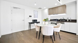 A modern kitchen with white cabinetry, a dining area with a round table and four chairs, and a small side table with a plant. - Waterloo Serenity Suite (Waterloo)