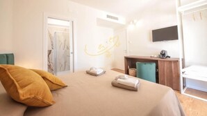 A hotel room with a bed, a desk, a television, and a bathroom with a shower.