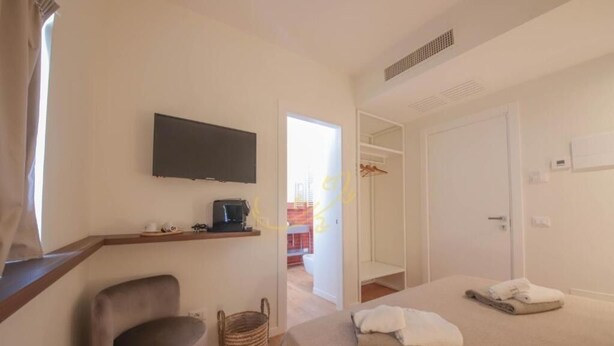 A hotel room with a bed, a chair, a television, and a small table with a coffee maker.