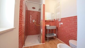 A bathroom with a shower, a sink, and a toilet.