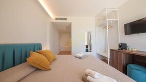 A modern hotel room with a bed, a TV, a desk, and a wardrobe.