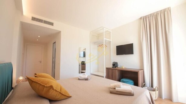 A hotel room with a bed, a desk, a TV, and a wardrobe.