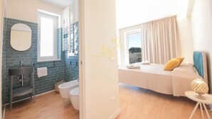 A modern bathroom with a blue-tiled wall, a round mirror, a sink, and a toilet.