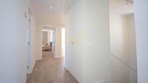 A hallway with a staircase and a door leading to a room.